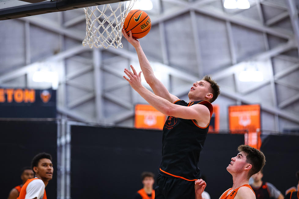 A man lifts a ball nearly to the rim of the basket.