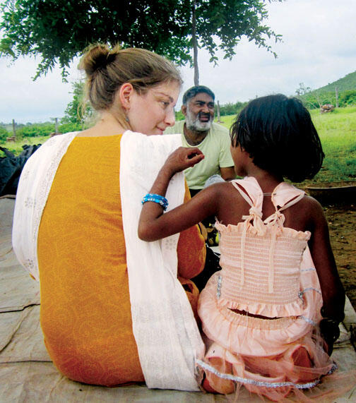 Shaina Watrous ’14, director of a documentary about Ajeet Singh, center, listens to a child in Varanasi, India.