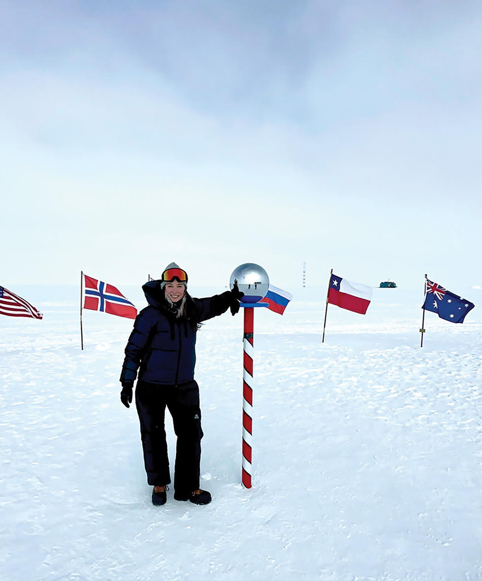 Grace Cordsen ’19 stands next to a pole in a circle of flags standing in the snow.