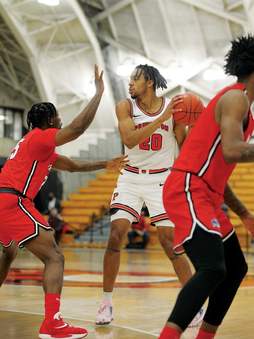 This is a photo of Tosan Evbuomwan ’23 playing against Marist in November. He's holding the ball to his left and looking right while another player tries to block him.