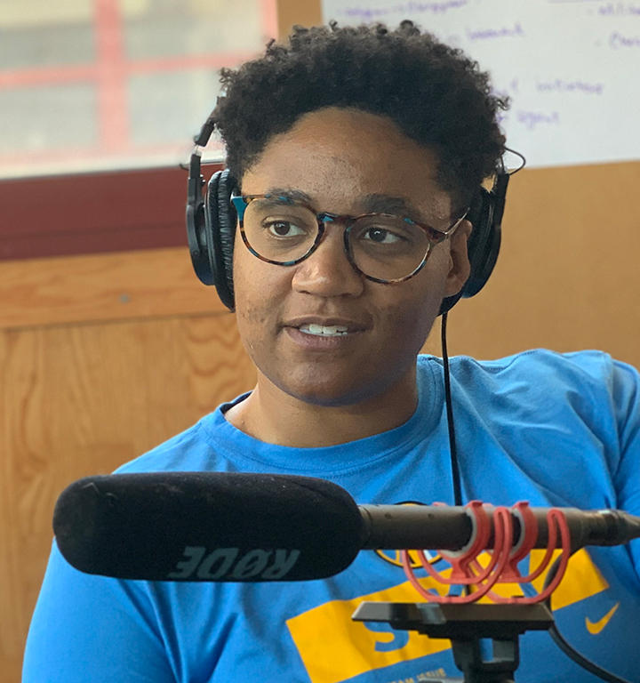 Erisa Apantaku ’14 wearing headphones in front of a microphone.