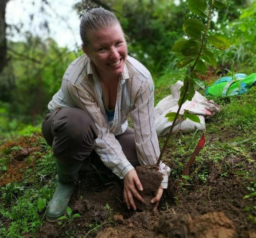 Ruth Metzel smiles as she lowers a plant into the ground.