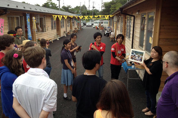 Students listen to a shopkeeper at a small shopping area in Onagawa created out of shipping containers.