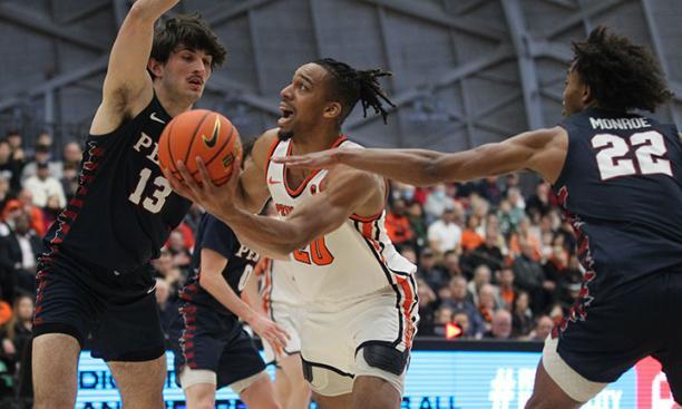 Tosan Evbuomwan ’23 splits two Penn defenders in Princeton’s 77-70 win at Jadwin Gym.